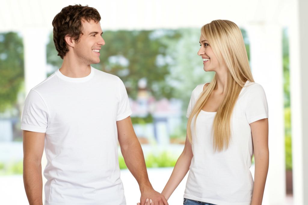 A happy couple smiling and holding hands, looking at each other with affection.