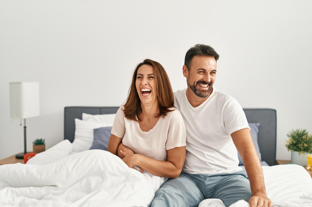 A happy middle-aged couple laughing and embracing in their bedroom.