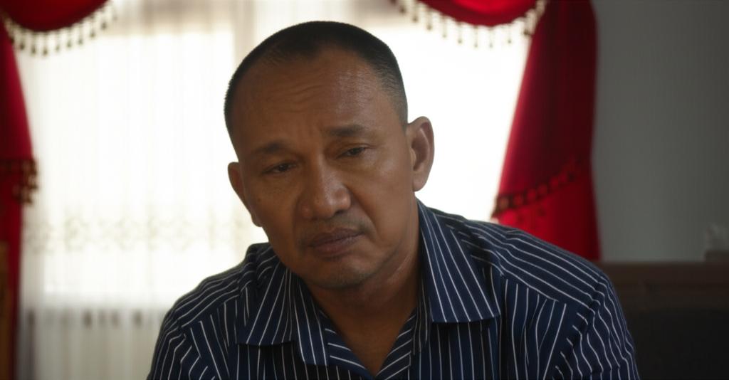 Middle-aged Indonesian man looking tired and thoughtful, sitting alone