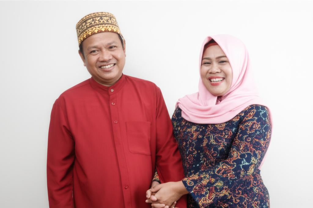 Middle-aged Indonesian couple smiling and holding hands affectionately, looking happy and connected